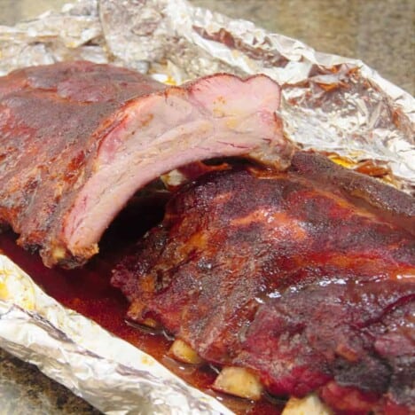 Finished rack of glazed pork ribs sliced to show the succulent interior of the cooked meat.