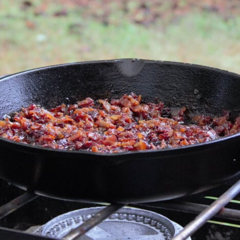 Bacon jam cooking at the moist but not wet stage in a iron skillet over a gas stove.