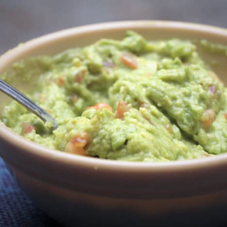 A tan bowl filled with ready to eat guacamole.