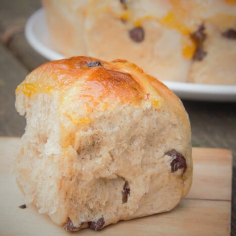 Close up of a single, fully baked hot cross bun with golden brown top.