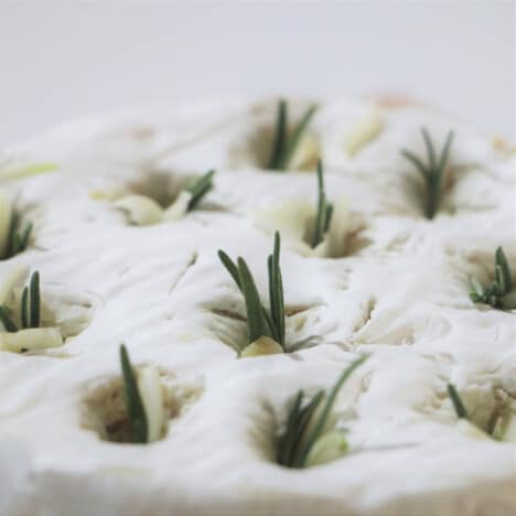 Close up of garlic and rosemary stuffed into the top of a round of Camembert.