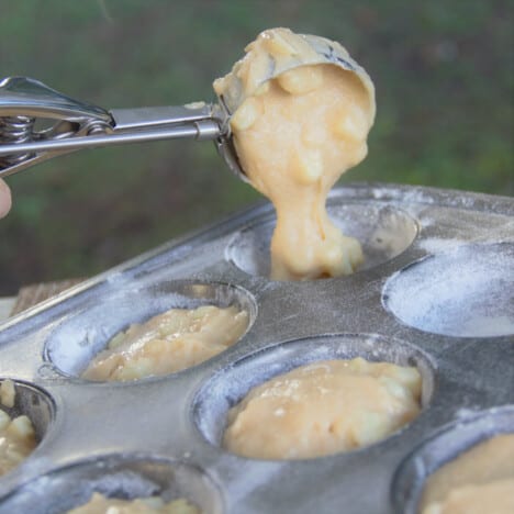 Apple and cinnamon batter being scooped into a muffin tray.