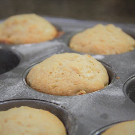 A close up of cooked apple and cinnamon muffins still in the baking tray where they were baked.