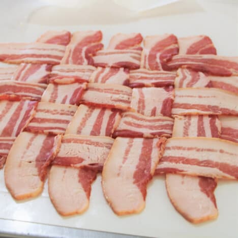 A lattice of bacon sitting prepared on a white chopping board.