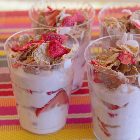 Four ready to eat plastic cups of strawberry breakfast parfaits.