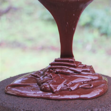 Chocolate ganache being poured on top of the chocolate cake.