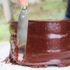 The chocolate ganache being smoothed on the sides of the cake with a pallet knife.