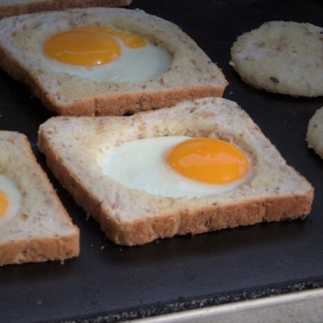 Several egg in bread on a flat top griddle.