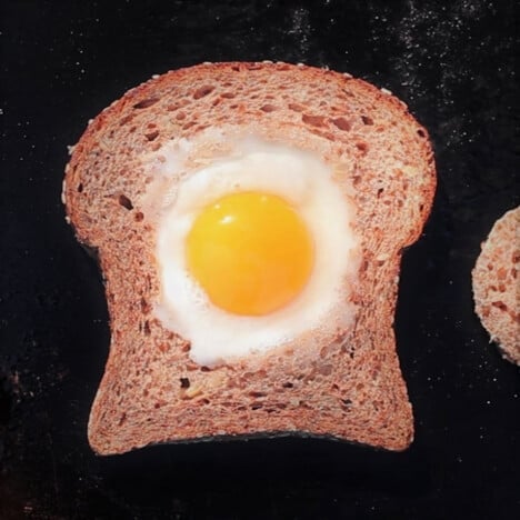 A slice of whole wheat bread with the center cut out and an egg cooked in the middle.