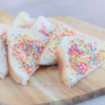 Triangular slices of white bread spread with margarine and topped by multi-colored sprinkles, sitting on a chopping board.