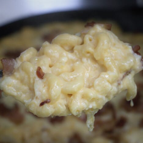 A large spoonful of mac and cheese with the full dish in the background.