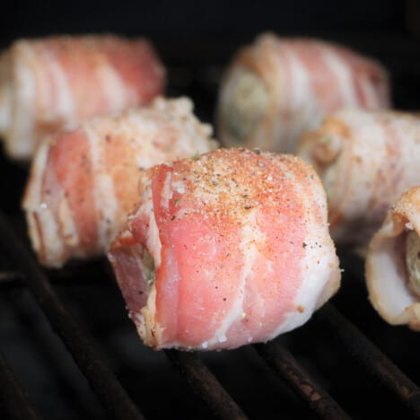 Moink balls sitting on a grate in a barbecue.