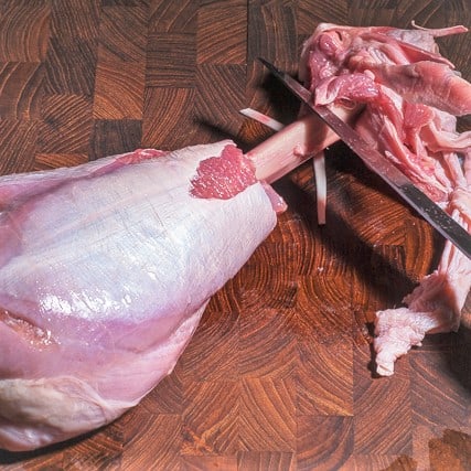 A turkey drumstick partly butchered.