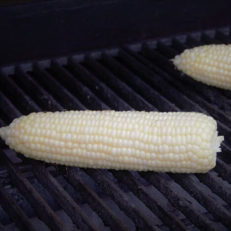 Corn with the husk off cooking on the grill.