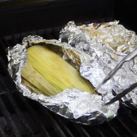 Foil being opened on a grill to exposed cooked corn.