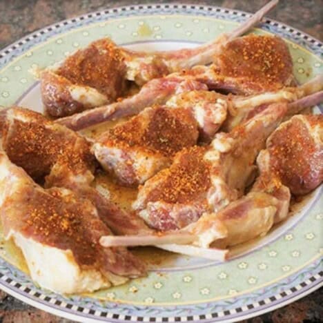 A plate of raw lamb chops sprinkled in a BBQ rub.
