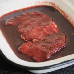 A rectangular enamel dish with a steak marinating in it.