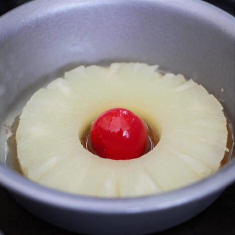A small cake tin with a pineapple ring and cherry sitting in the base.