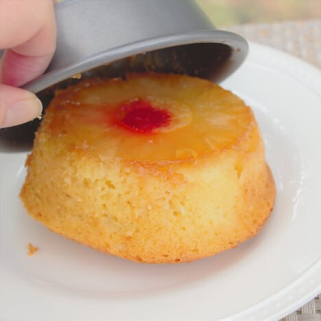 The pina colada cake being removed from the small cake tin onto a serving plate.