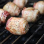BBQ Moink Balls cooking on a grill grate.