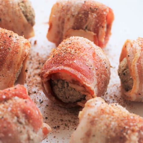 BBQ Moink balls sitting on a chopping board covered with a sprinkling of BBQ rub.