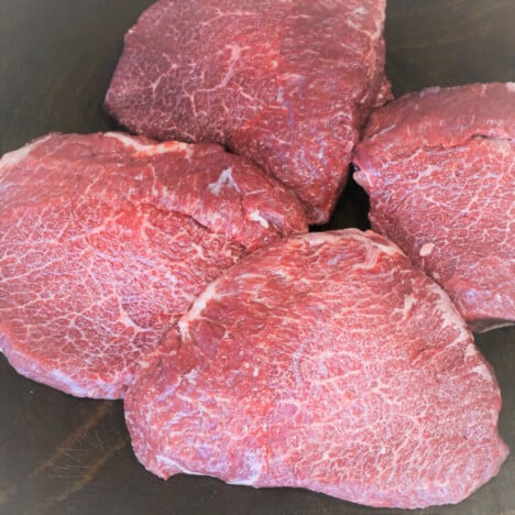 Four raw beef cheeks trimmed and ready to cook.