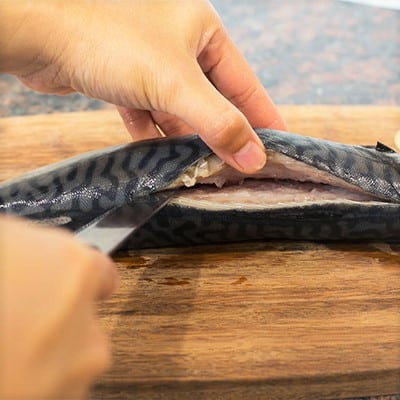 Slicing a fish down the center along the spine.