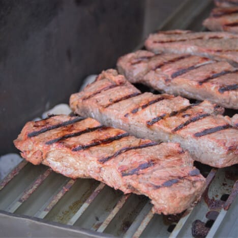 A grill with a row of New York steaks having parallel grill marks on them.