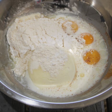 A stainless bowl with the flour, ricotta, and three eggs ready to be combined.