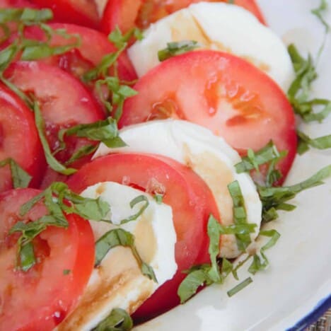 A close up of sliced tomatoes and mozzarella with sliced basil.