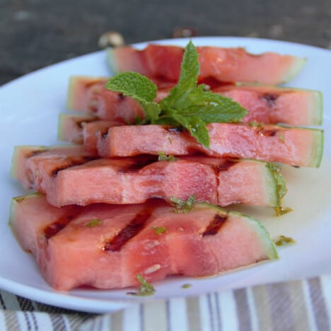A plate of grilled watermelon slices garnished with mint.
