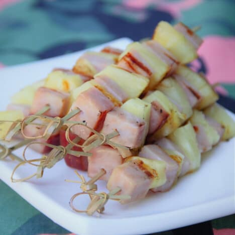 Ham and pineapple kebabs on a white serving plate.