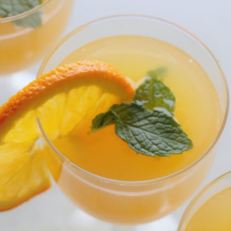 Looking down on a mocktail with a garnish of a slice of orange and mint leaves.