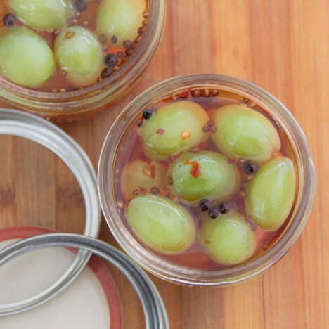 Looking down at two jars of pickled grapes sitting on a chopping board.