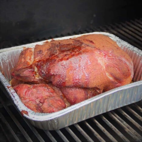 A smoked pork butt in a half pan on the grill.