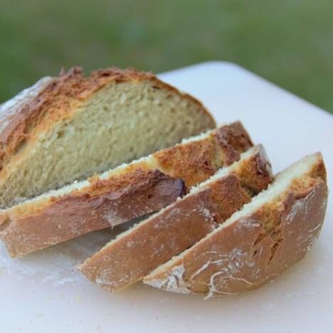 Soda bread is sliced on a white cutting board and ready to eat.