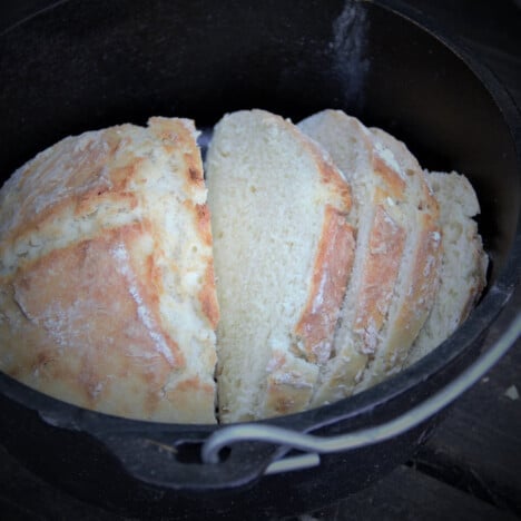 A half sliced soda bread sitting in a Dutch oven.