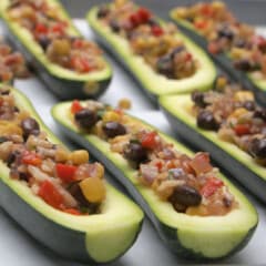 Hollowed out zucchini stuffed with a colorful filling laid out on a baking tray ready to be cooked.