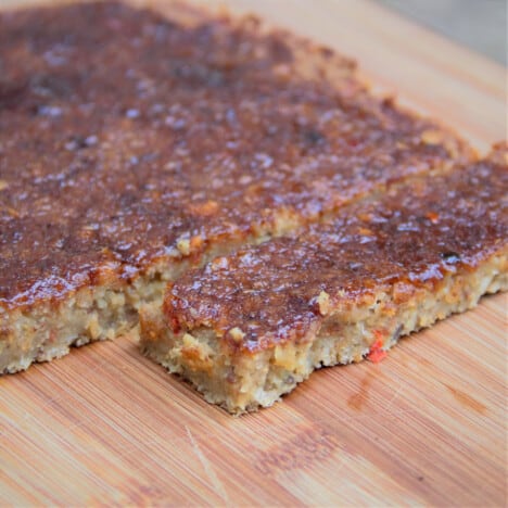 The BBQ chickpea loaf is on a chopping board after being sliced and ready to serve.