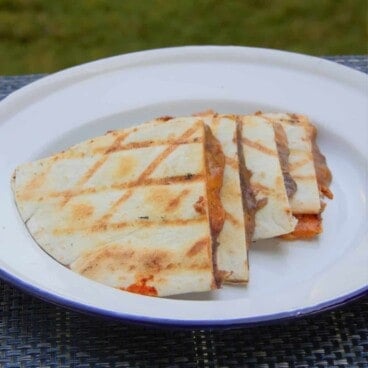 A black bean and salsa quesadilla quartered and served on a camp plate.