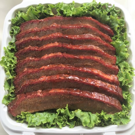 A bed of lettuce with neat slices of smoked brisket flat laid in it.