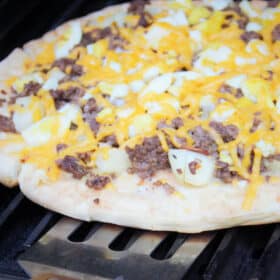 The breakfast pizza being rotated on the grill