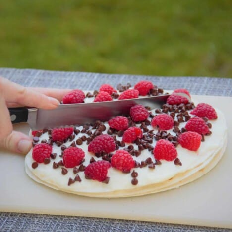 A knife cutting a grilled chocolate raspberry quesadilla in half.