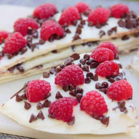 A grilled chocolate raspberry quesadilla is sliced in half on a cutting board.