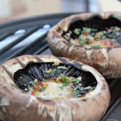 Large portobello mushrooms with herb oil are on a round grill.