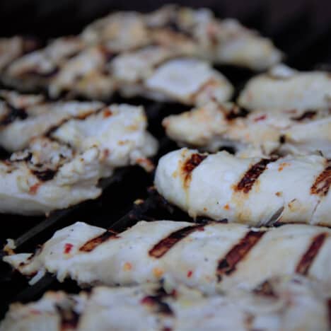 Chicken tenders with deep hatch marks on the grill.