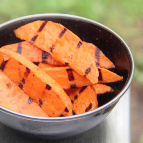 A stainless steel bowl holds a pile of grilled sweet potatoes.
