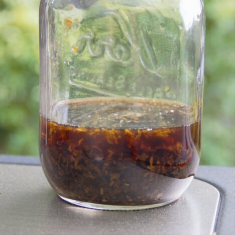 A jar on mint sauce sitting on a table.