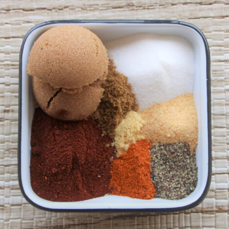 Looking down on a square plate of various herbs and spices.