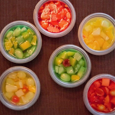 Looking down on various colors of Jello cups with fruits mixed in.